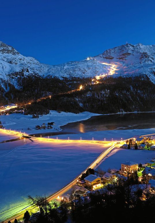 ENGADIN ST. MORITZ - Snownight auf dem Corvatsch - Blick von Silvaplana auf die laengste beleuchtete Skipiste (4.1 km) der Schweiz. Die beleuchtete Piste beginnt an der Mittelstation Corvatsch und geht ueber die Waldkerbe der Surlej-Piste zur Talstation, oberhalb des Ortes Surlej. Im Vordergrund die Lichter des Ortes Silvaplana.

Snow-night at Corvatsch - View from Silvaplana towards the longest illuminated ski slope of Switzerland (4.1 km). The illuminated slope begins at the middle station of Corvatsch and goes along the tree notch of the Surlej slope down to the station at the bottom which is just above the houses of Surlej. In the foreground the lights of the village of Silvaplana.

Snownight al Corvatsch - Vista da Silvaplana sulla piu lunga pista da sci illuminata della Svizzera (4.1 km). La pista illuminata comincia nella stazione intermedia del Corvatsch e va lungo il bosco della pista Surlej fino alla stazione nella valle al di sopra del paese di Surlej. In primo piano l'illuminazione di Silvaplana.

Copyright by ENGADIN St. Moritz By-line:swiss-image.ch/Robert Boesch